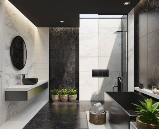 Trendy and modern home spa bathroom with matte black and white marble tiles, black stone wall in bath and stove light. Plants for cozy interior. Modern black bath tub. Candles light. Big roof window. Marble stone floor. 3d rendering.